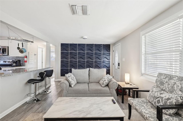 living area featuring light wood finished floors, visible vents, and baseboards