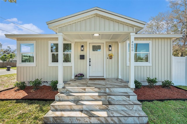 property entrance featuring covered porch and fence