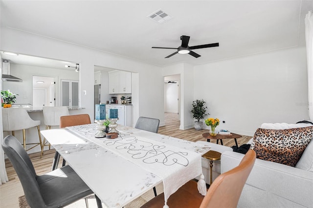 dining room featuring light wood-style flooring, visible vents, ceiling fan, and baseboards