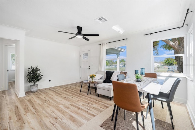 dining room with ceiling fan, light wood finished floors, visible vents, and baseboards