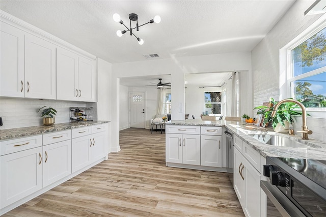 kitchen featuring visible vents, backsplash, light wood-style floors, white cabinetry, and a sink