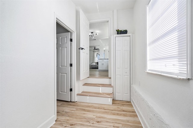 hallway featuring light wood-style flooring and baseboards