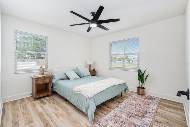 bedroom featuring light wood-style floors, multiple windows, baseboards, and a ceiling fan