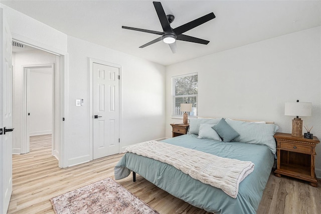 bedroom featuring light wood-style floors, baseboards, visible vents, and a ceiling fan