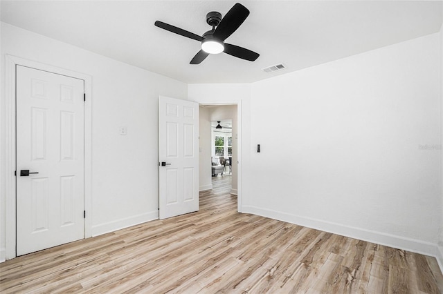 spare room featuring light wood-type flooring, visible vents, and baseboards