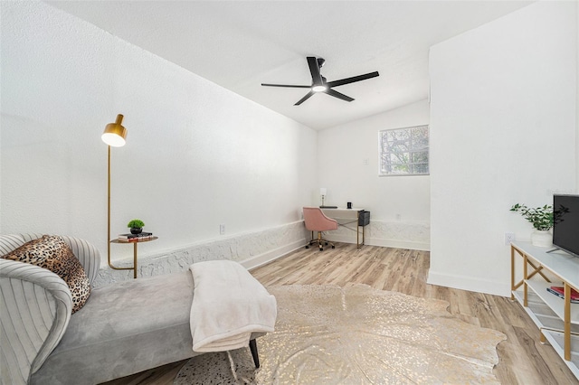 living area featuring a ceiling fan, vaulted ceiling, baseboards, and wood finished floors