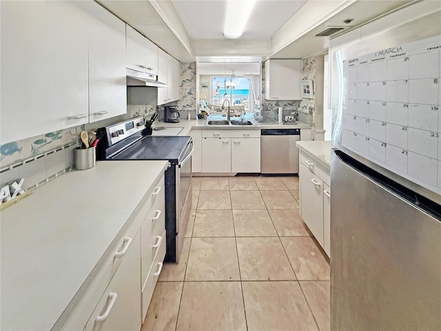 kitchen featuring light tile patterned flooring, under cabinet range hood, a sink, appliances with stainless steel finishes, and backsplash