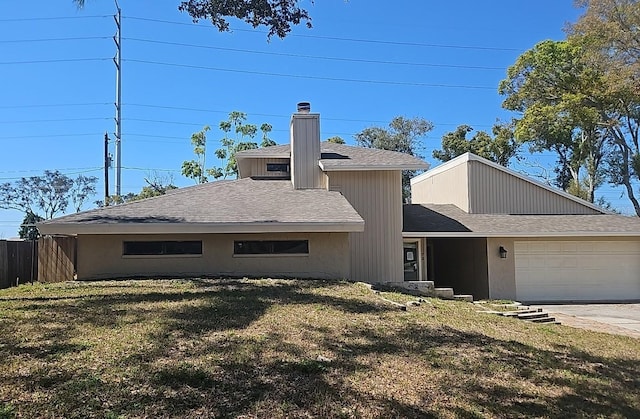 view of front of property with a chimney, a shingled roof, a front yard, fence, and a garage