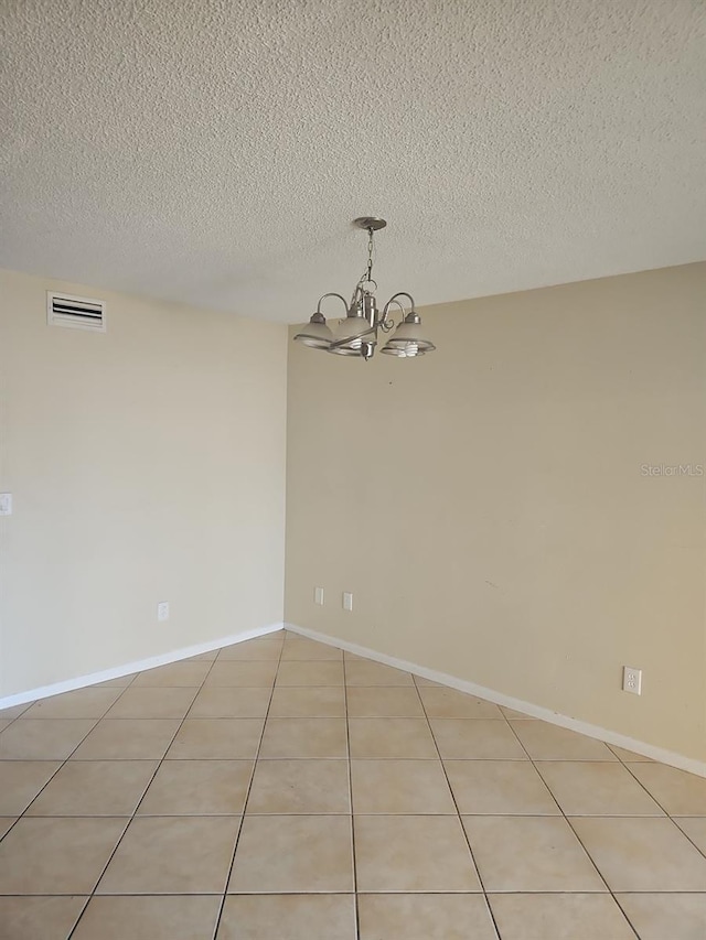 spare room featuring visible vents, a notable chandelier, baseboards, and light tile patterned floors