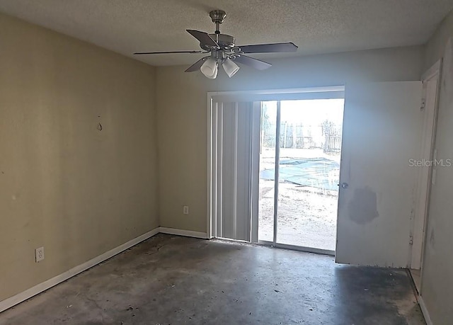 spare room with ceiling fan, concrete floors, baseboards, and a textured ceiling