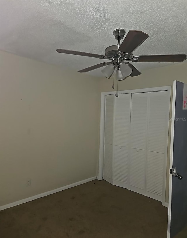 unfurnished bedroom with a closet, a ceiling fan, dark colored carpet, and a textured ceiling