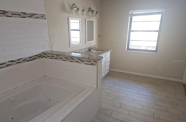 full bathroom featuring a jetted tub, tile patterned floors, vanity, and baseboards