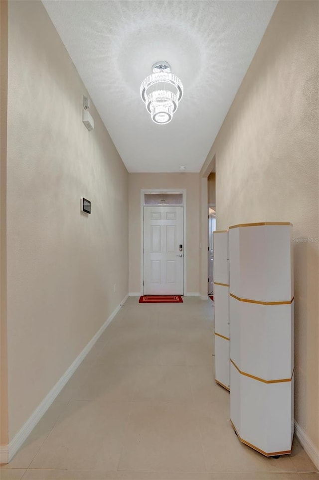 corridor with a notable chandelier and baseboards