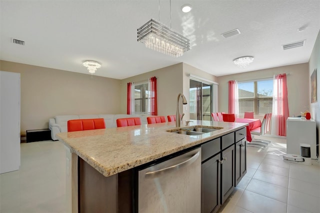 kitchen featuring visible vents, a center island with sink, a sink, stainless steel dishwasher, and open floor plan