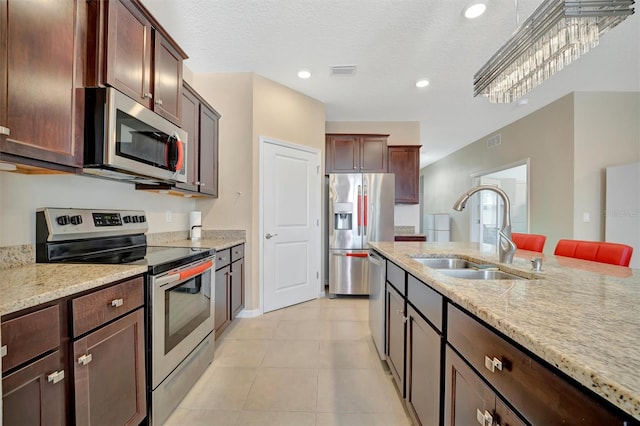 kitchen with a sink, light stone counters, visible vents, and stainless steel appliances