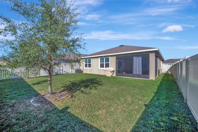 back of property with stucco siding, a lawn, central AC, and a fenced backyard