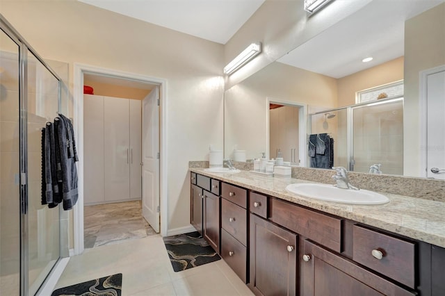 bathroom featuring double vanity, a stall shower, baseboards, and a sink