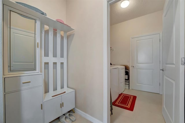 clothes washing area featuring light tile patterned floors, baseboards, washing machine and dryer, and laundry area