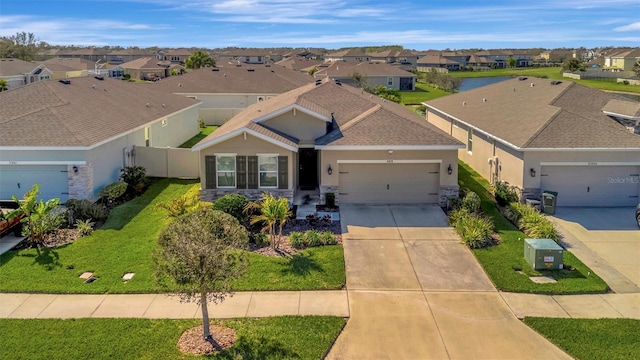 view of front facade featuring a residential view, an attached garage, concrete driveway, and a front lawn