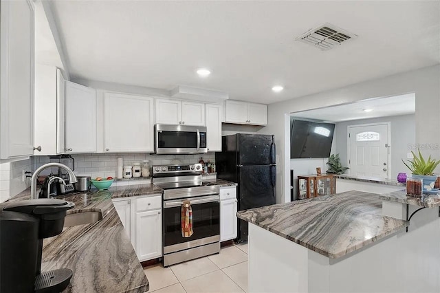 kitchen featuring dark stone counters, appliances with stainless steel finishes, visible vents, and white cabinetry