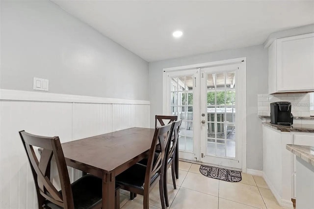 dining space featuring a wainscoted wall, light tile patterned flooring, and french doors