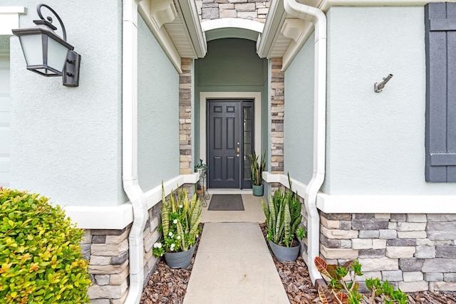 view of exterior entry featuring stone siding and stucco siding