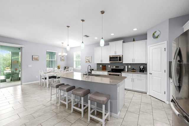 kitchen featuring a sink, white cabinetry, stainless steel appliances, a breakfast bar area, and decorative backsplash