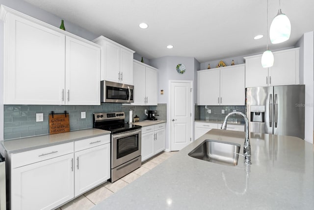 kitchen with white cabinetry, decorative light fixtures, appliances with stainless steel finishes, and a sink