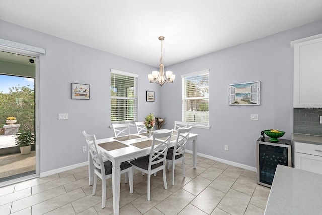 dining space with light tile patterned floors, baseboards, an inviting chandelier, and beverage cooler