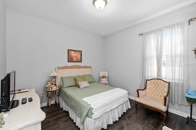 bedroom with a textured ceiling, baseboards, and wood finished floors