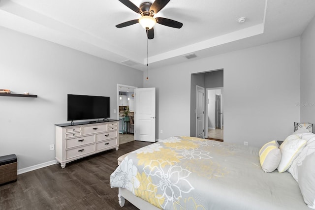 bedroom featuring visible vents, baseboards, a tray ceiling, a ceiling fan, and dark wood-style flooring