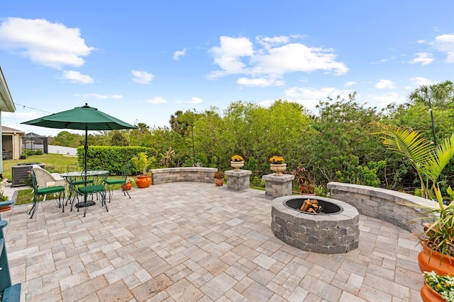 view of patio with outdoor dining area, a fire pit, and central AC