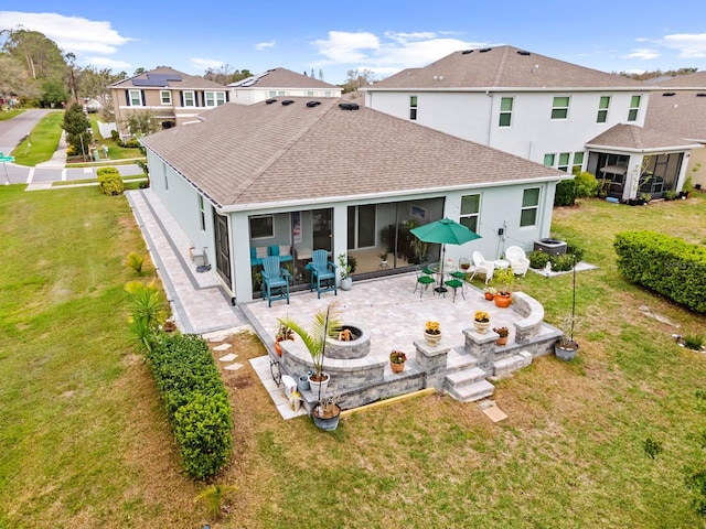 rear view of house featuring stucco siding, an outdoor fire pit, a yard, a sunroom, and a patio area