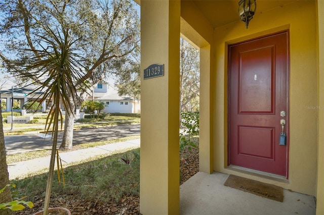 property entrance featuring covered porch and stucco siding