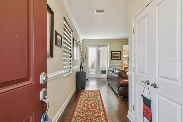 hallway featuring french doors, crown molding, visible vents, dark wood-type flooring, and baseboards