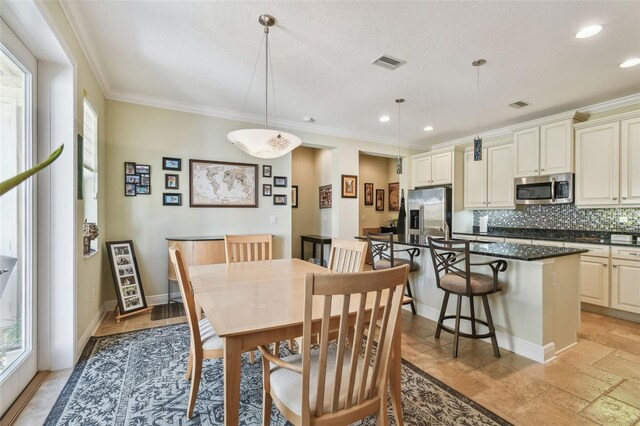 dining room with visible vents, ornamental molding, and a wealth of natural light