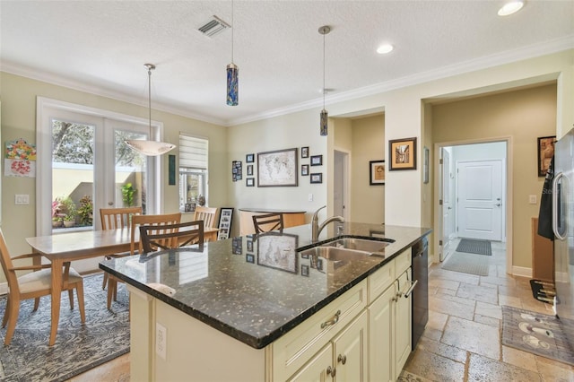 kitchen with cream cabinetry, stone tile floors, visible vents, a sink, and baseboards