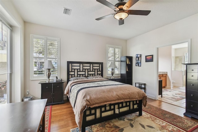 bedroom featuring light wood-style flooring, visible vents, baseboards, and ensuite bathroom