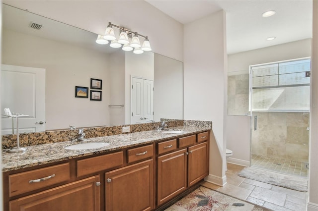 full bath featuring stone tile floors, visible vents, toilet, a sink, and a shower stall