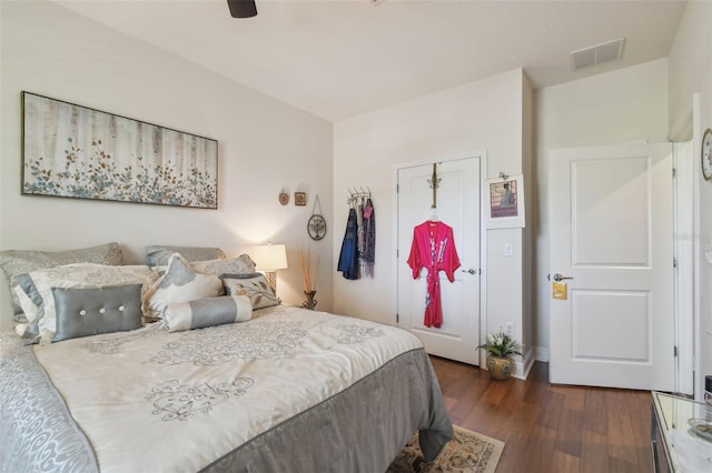 bedroom featuring a ceiling fan, visible vents, dark wood finished floors, and a closet