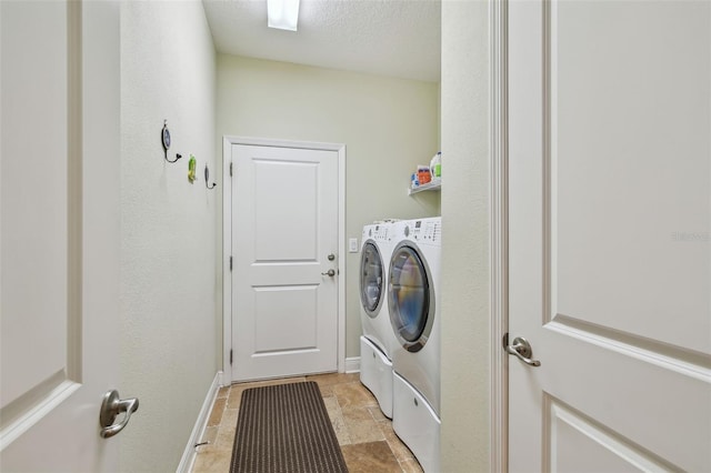 laundry area featuring laundry area, baseboards, washing machine and clothes dryer, stone finish flooring, and a textured ceiling