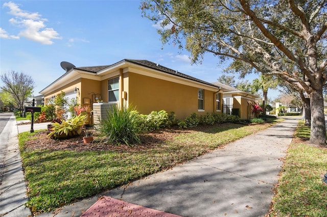 view of side of property featuring central AC, an attached garage, and stucco siding