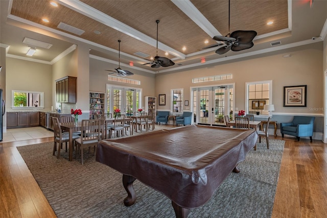 game room with light wood finished floors, french doors, and a raised ceiling