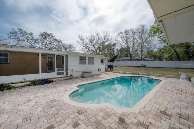 view of swimming pool with a lawn, a fenced in pool, a sunroom, a fenced backyard, and a patio area