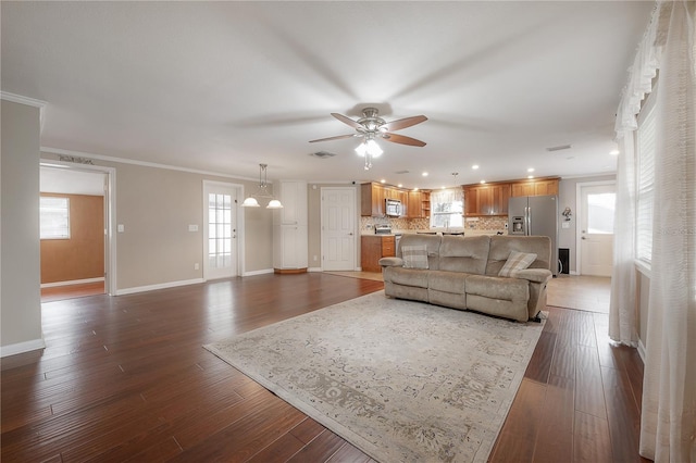 living room featuring dark wood-type flooring, visible vents, ornamental molding, and baseboards