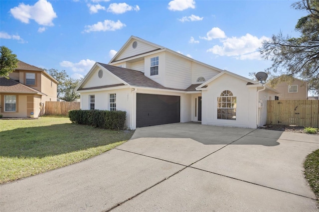 traditional-style house featuring a garage, fence, driveway, stucco siding, and a front yard