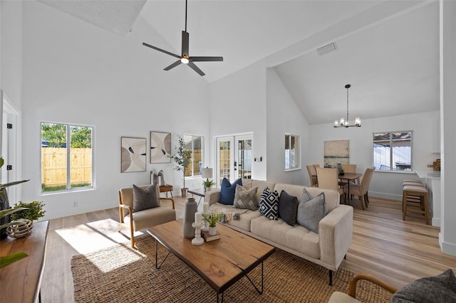 living room with light wood-type flooring, baseboards, visible vents, and ceiling fan with notable chandelier