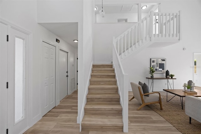 stairs featuring a towering ceiling and wood finished floors