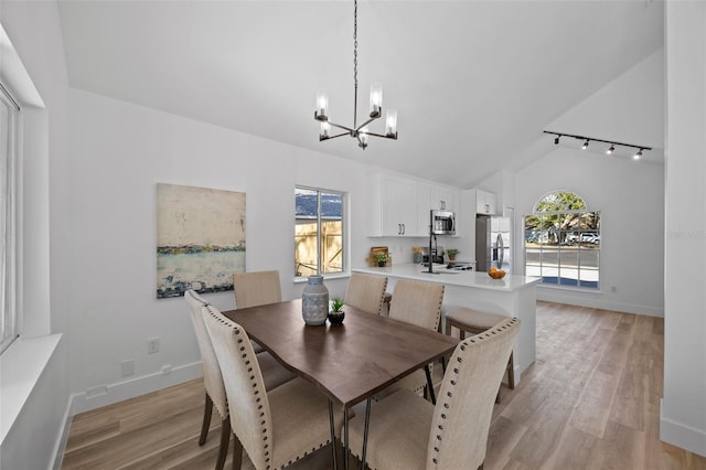 dining room featuring lofted ceiling, an inviting chandelier, baseboards, and light wood-style floors