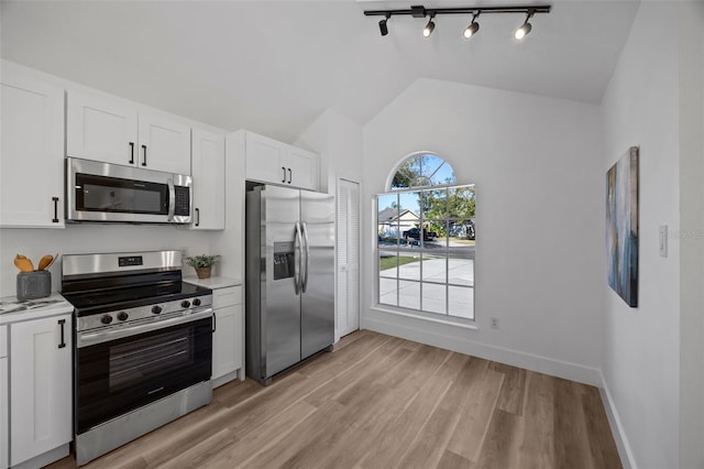 kitchen featuring stainless steel appliances, lofted ceiling, white cabinets, and light countertops